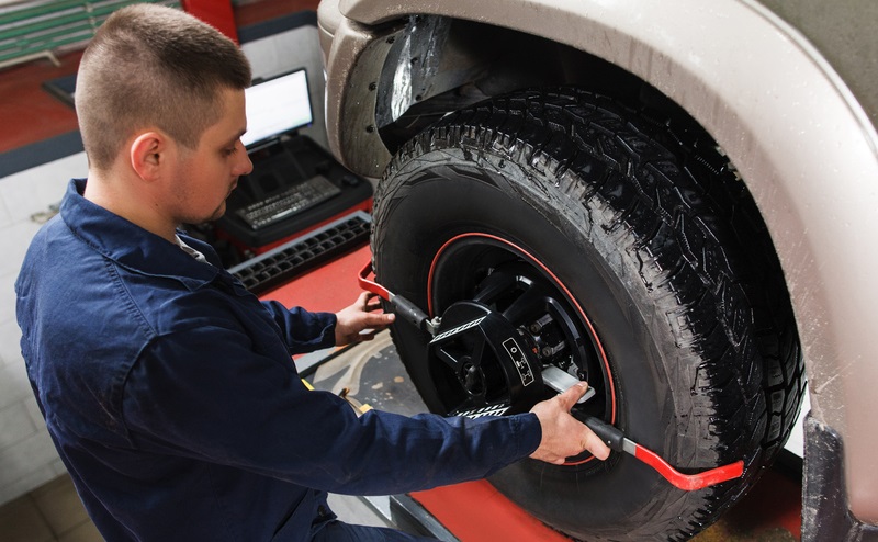 A mechanic performing a tire alignment on a vehicle.